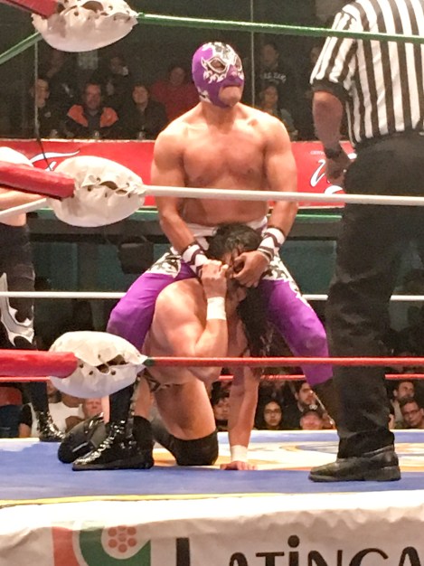 Mexican wrestler pulling another guy by the nostrils
